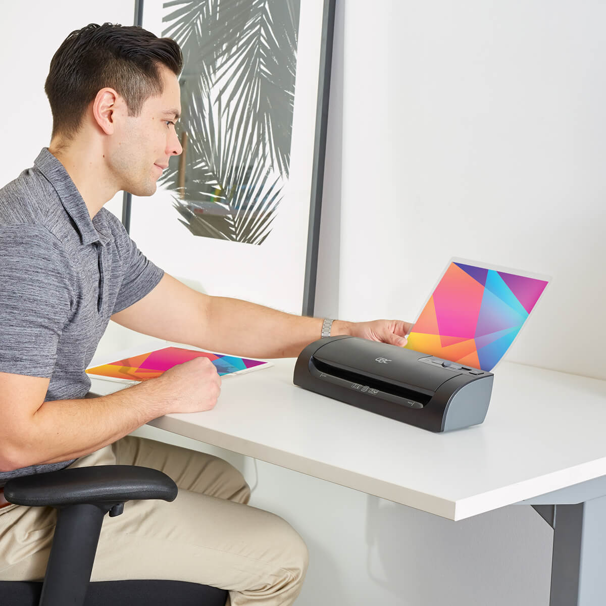 Homem sentado numa mesa de escritório usando a plastificadora de papel