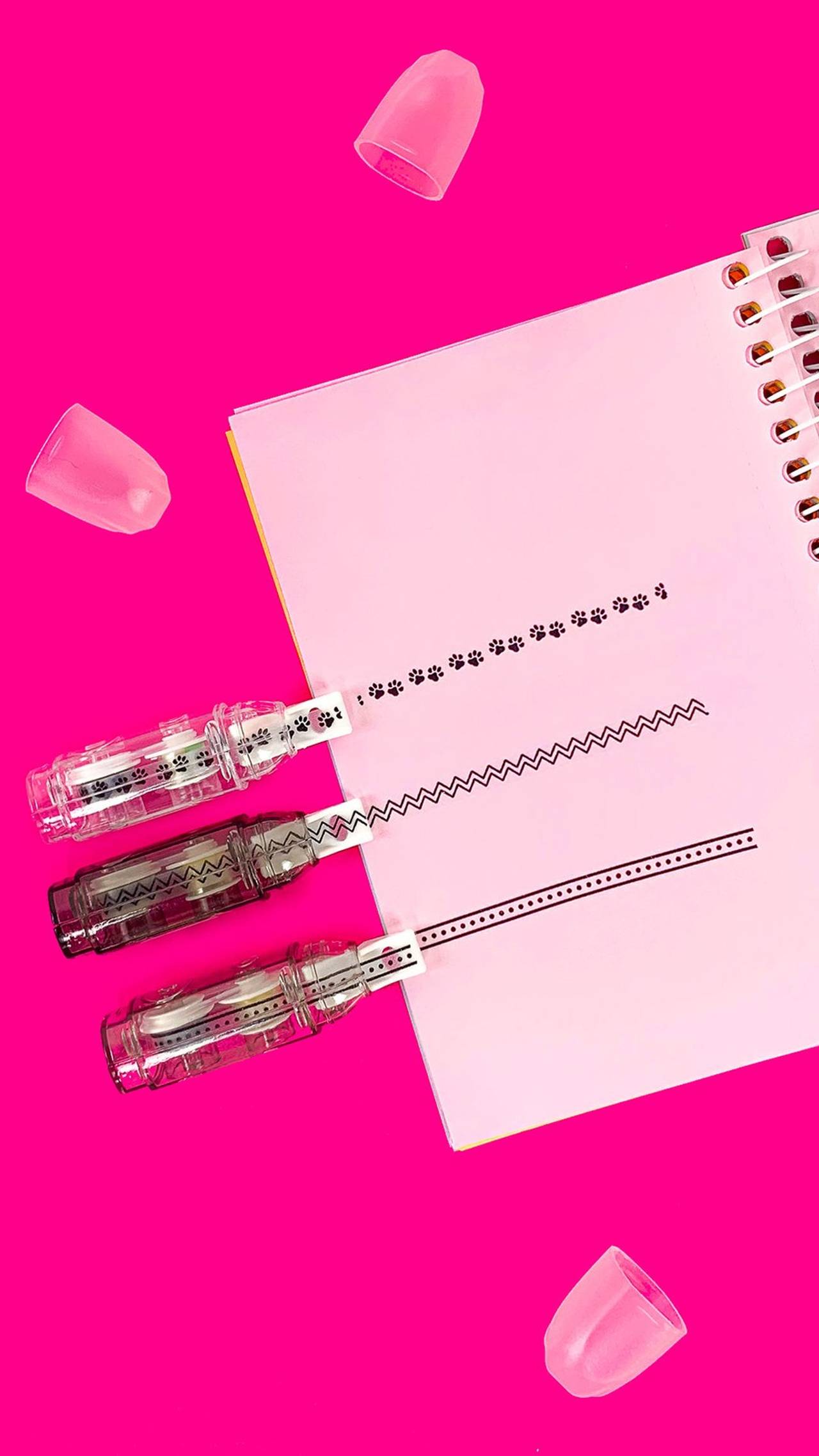 Papel rosa vibrante com linhas de fita adesiva decorativa e tampas de caneta