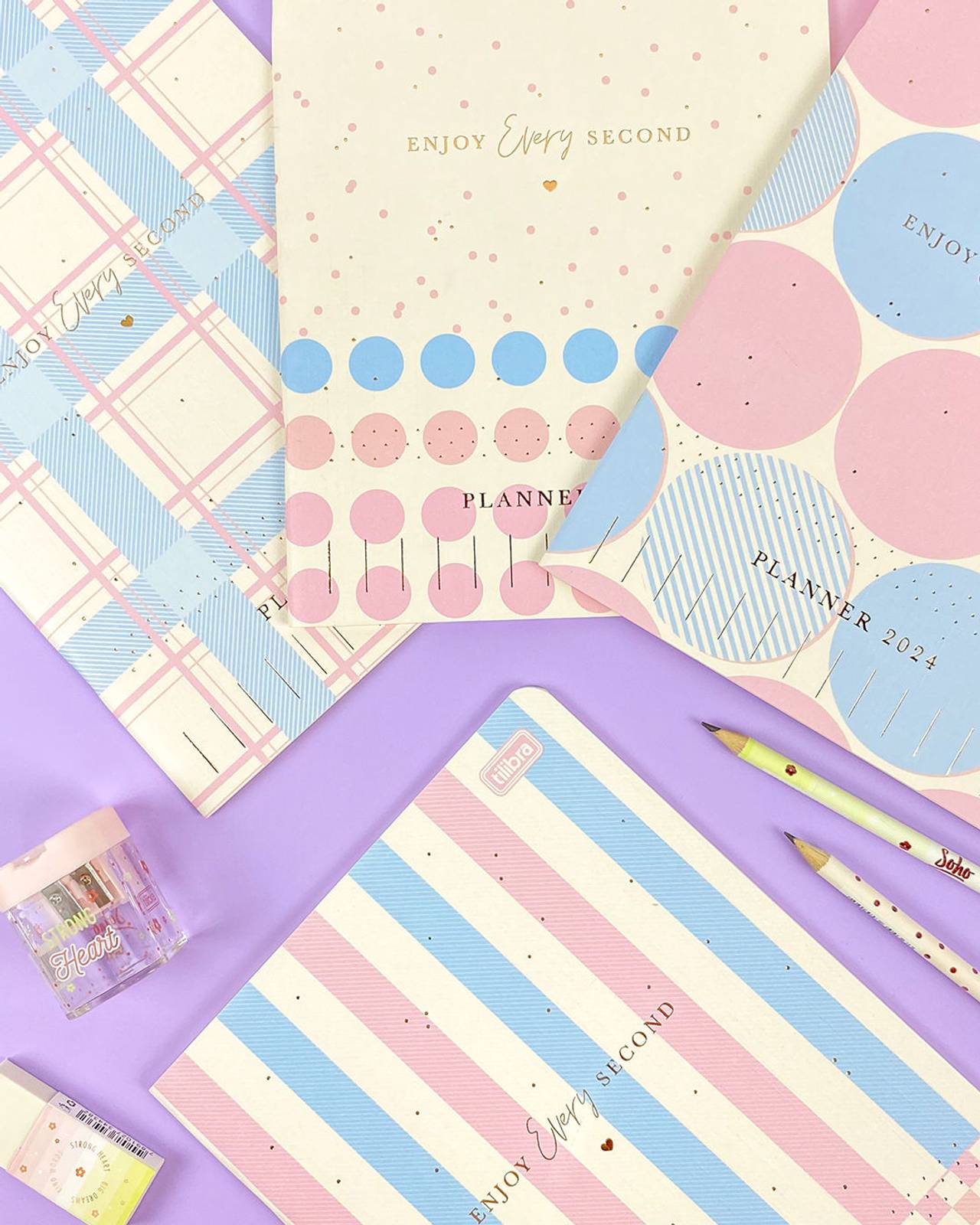 Planners coloridos e itens de papelaria em fundo lilás