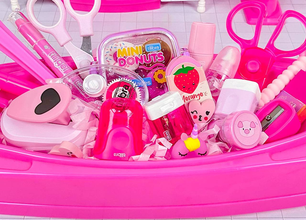 itens escolares em tons de rosa, como tesoura, grampeador, canetas, e borrachas, organizados em uma bandeja rosa 
