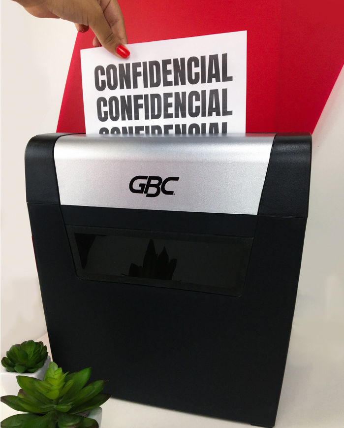 Pessoa colocando uma folha escrito "confidencial" em fragmentadora da marca GBC