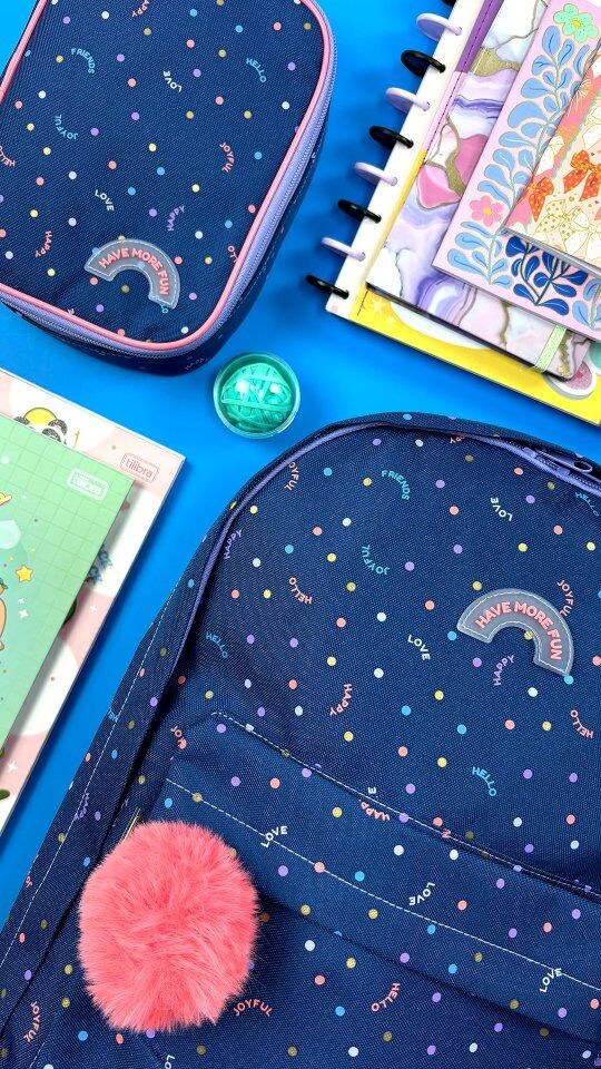 Mochila azul com bolinhas coloridas e pompom rosa