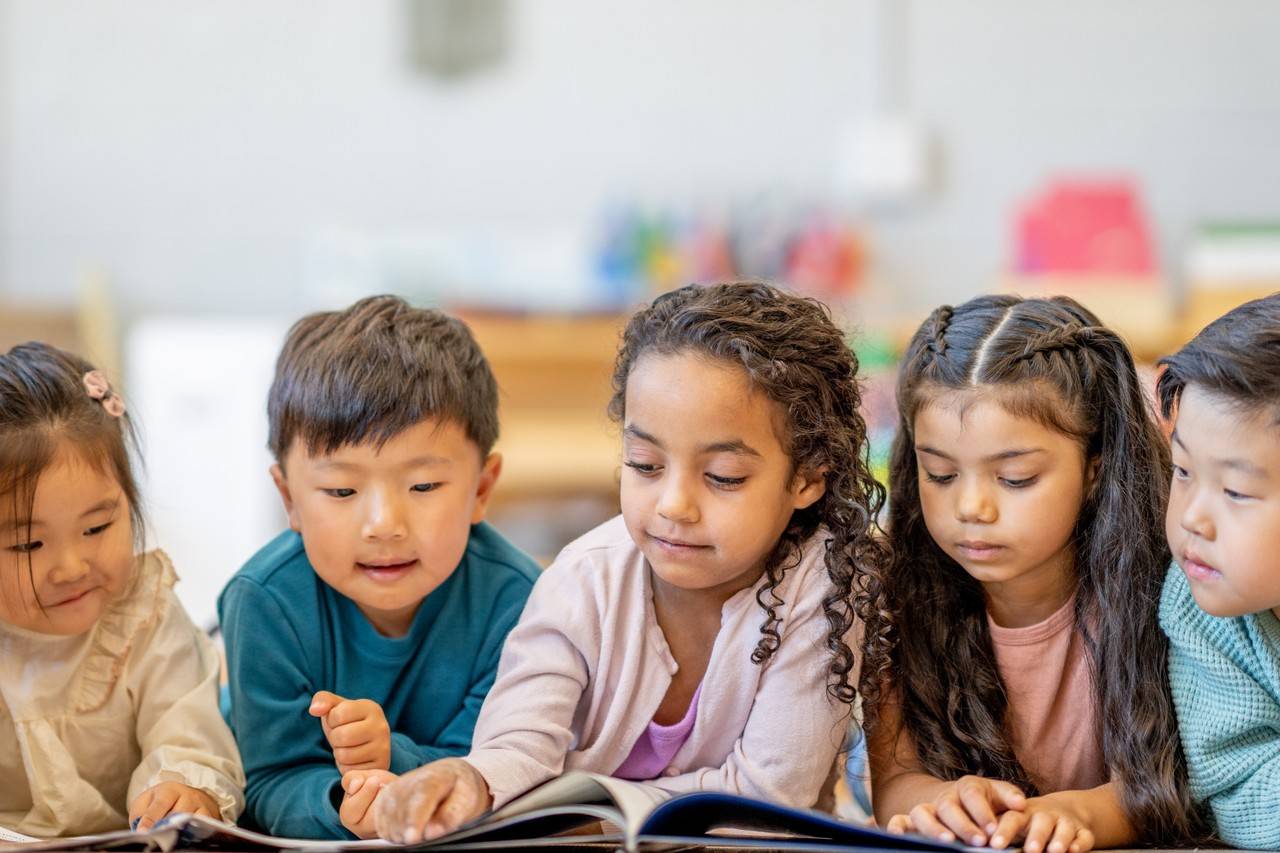 5 criança lendo o mesmo livro 2 meninos e 3 meninas