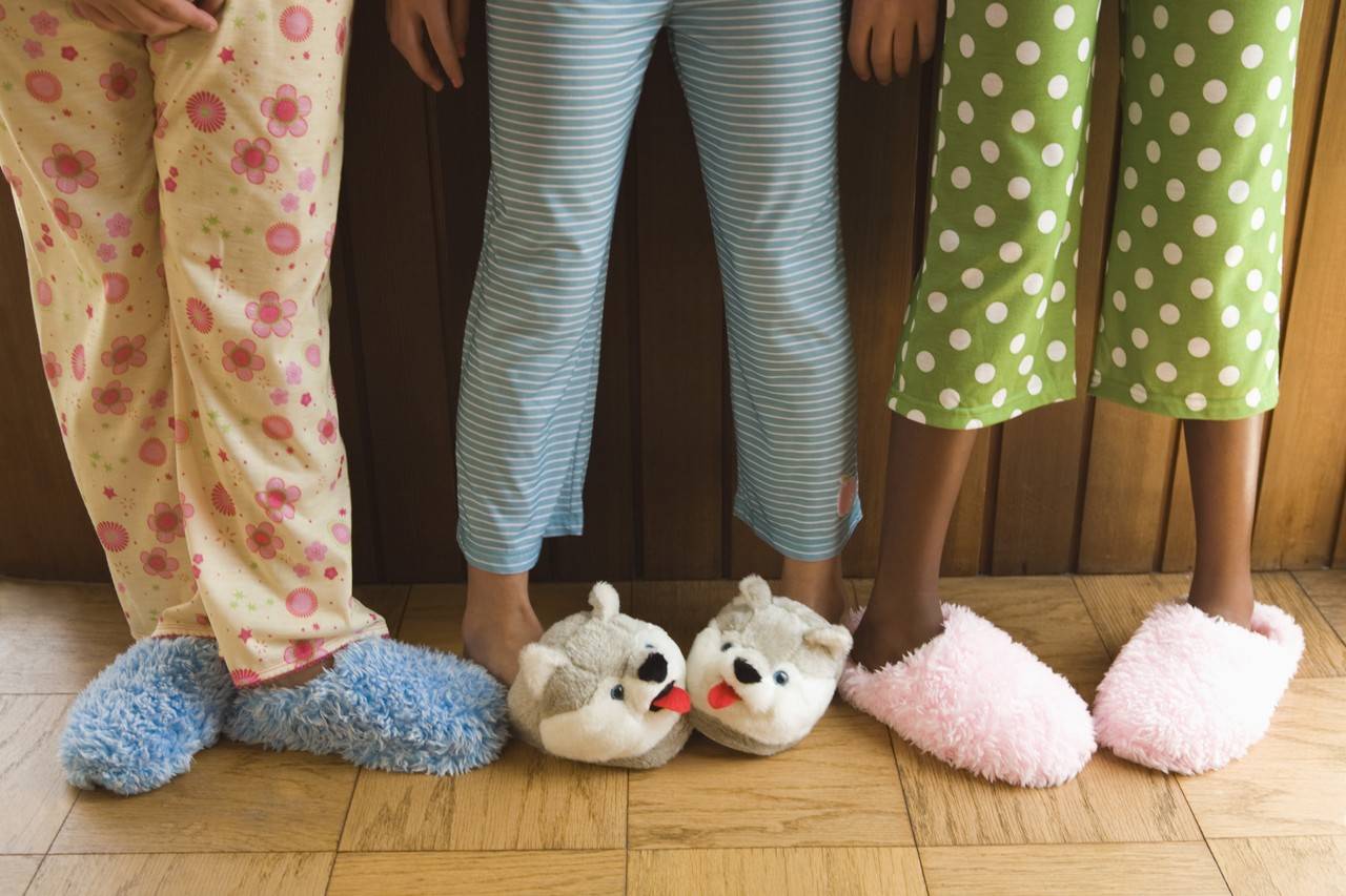 Pernas de 3 garotas de pijamas com pantufas no pes.