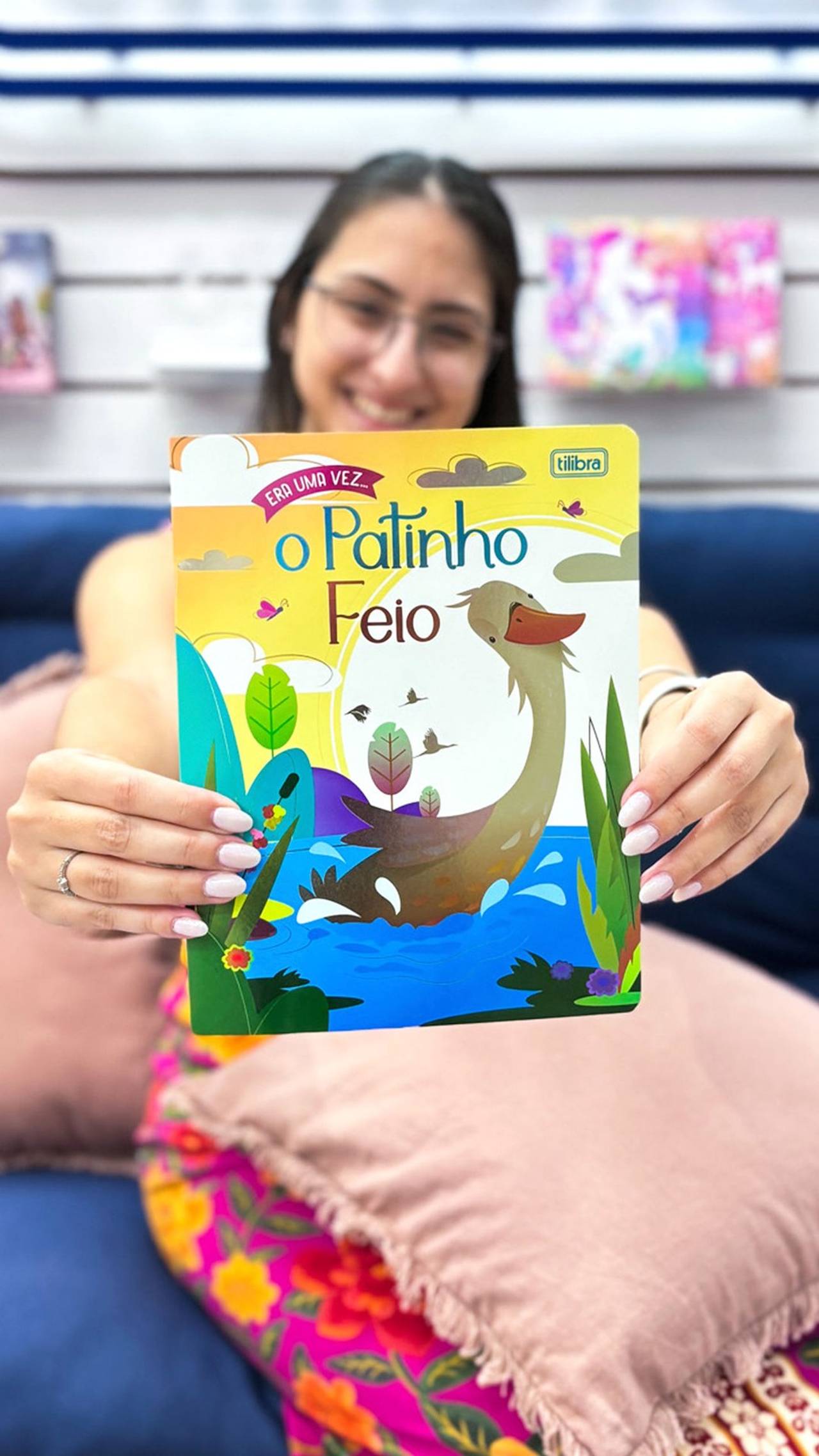 Menina sorrindo mostrando um livro do patinho feio