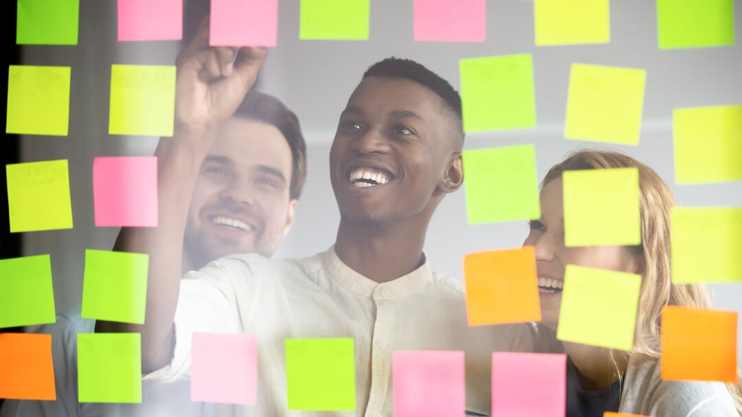 Equipes colaborando com post-its coloridos.
