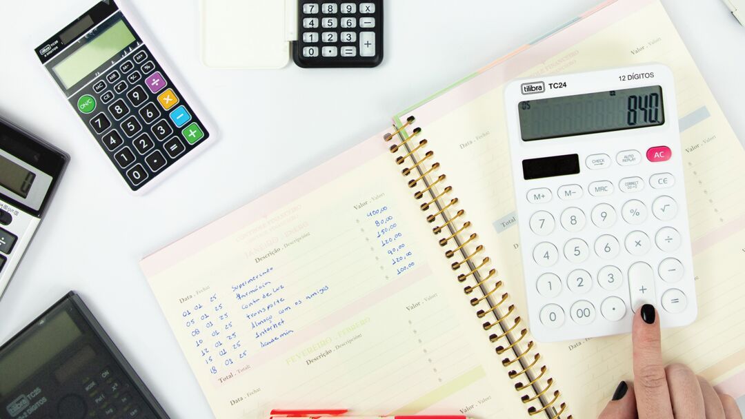 Calculadora sobre um caderno e outros aparelhos de cálculo.