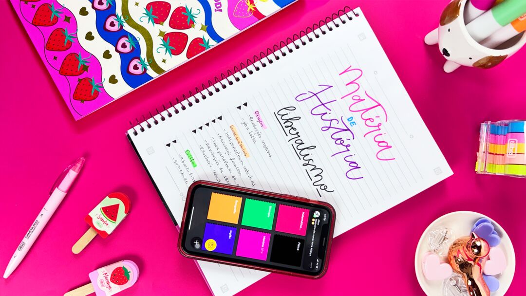Caderno de História com canetas coloridas em fundo rosa