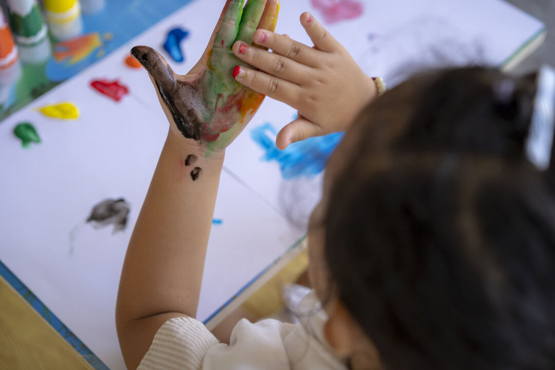 Criança pintando com as mãos em mesa de arte