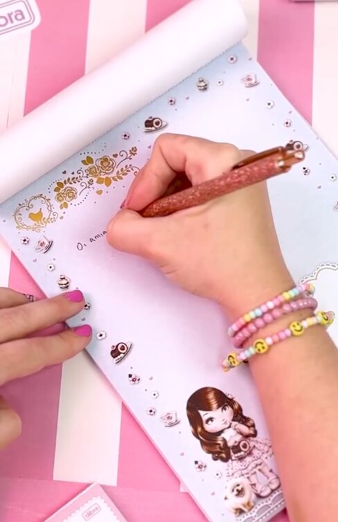 Mão escrevendo em papel decorado com adesivos