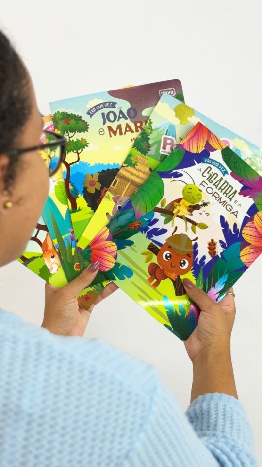 Pessoa segurando livros infantis ilustrados coloridos.