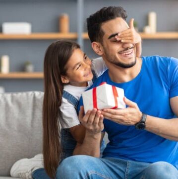 Pai e filha sorrindo com presente surpresa